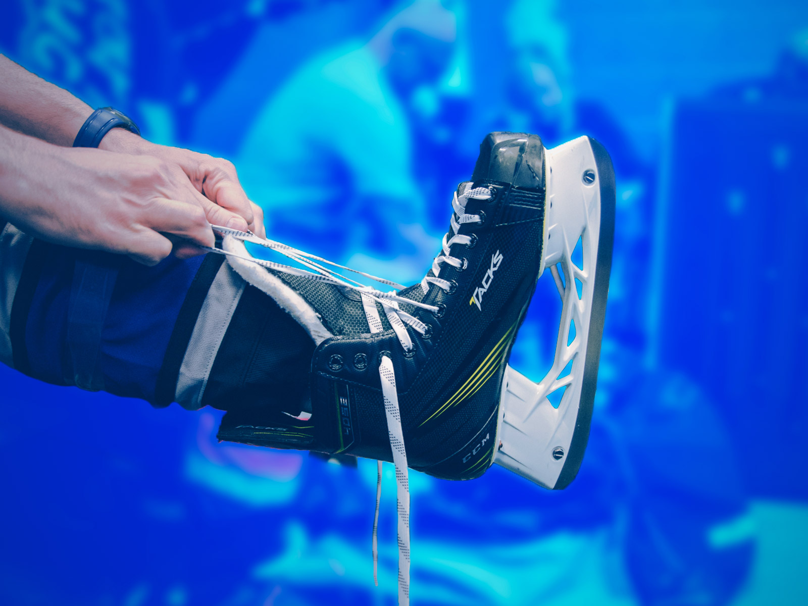 hands tying laces on CCM hockey skates